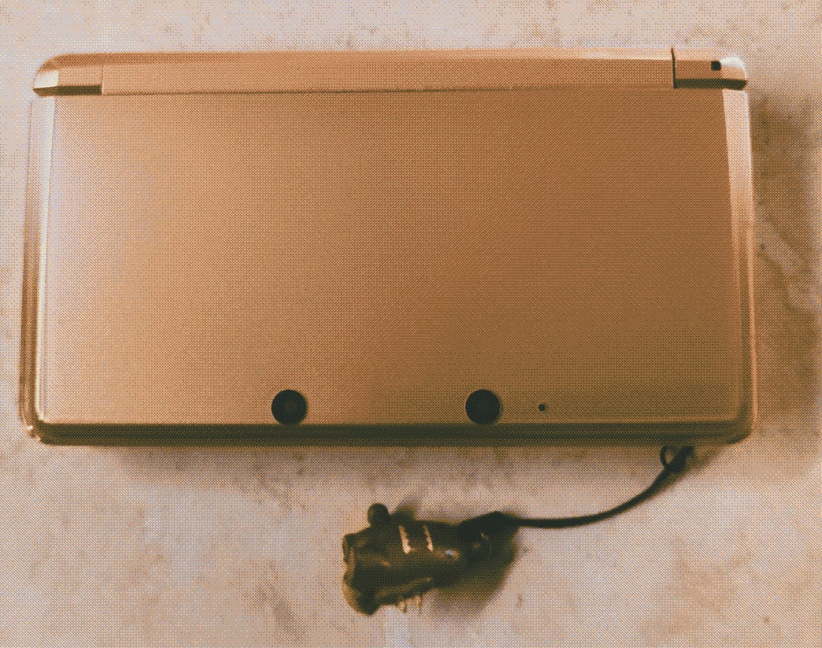 Picture of my pink 3DS, closed, with a little Domo phone charm attached.
