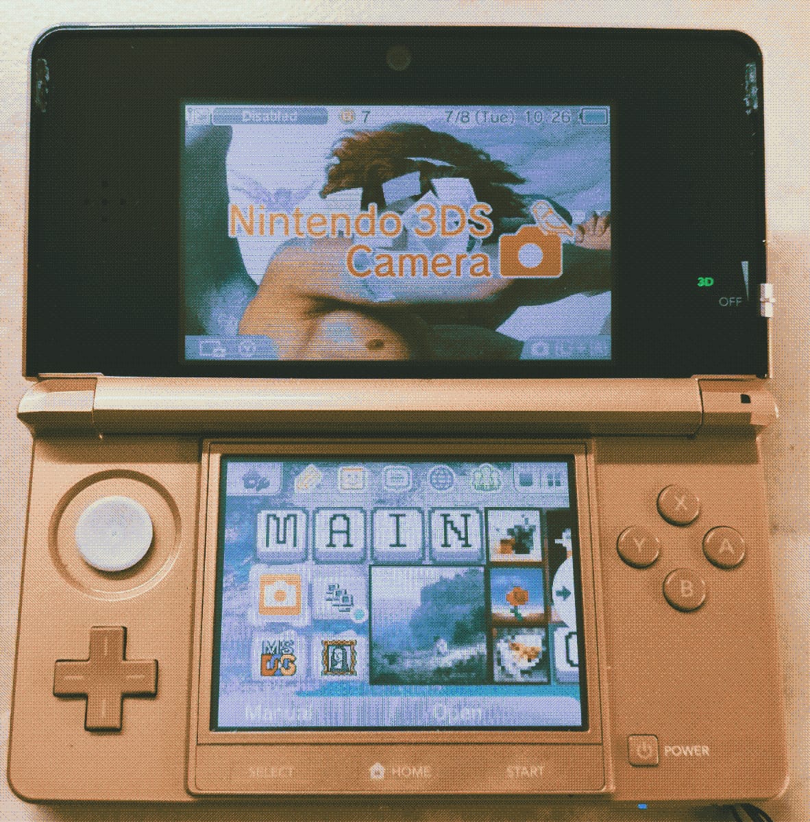 Picture of my pink 3DS, open, showing the main menu. Top screen shows the Fallen Angel background with the Nintendo 3DS Camera on top of it. Bottom screen displays the Main section of the 3DS. Folding with various apps sit in this section, along with a few Minecraft paintings.